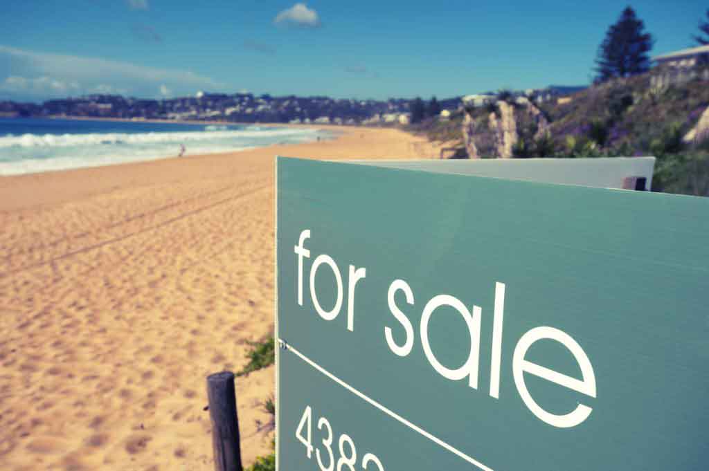 Real estate for sale sign on a beach